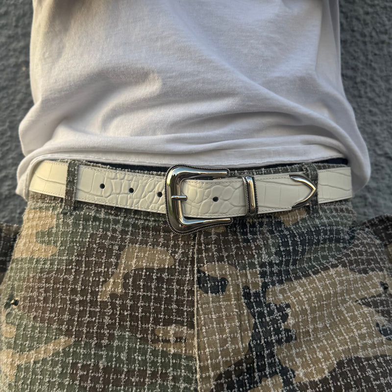Person wearing a white shirt, camouflage pants, and a belt 