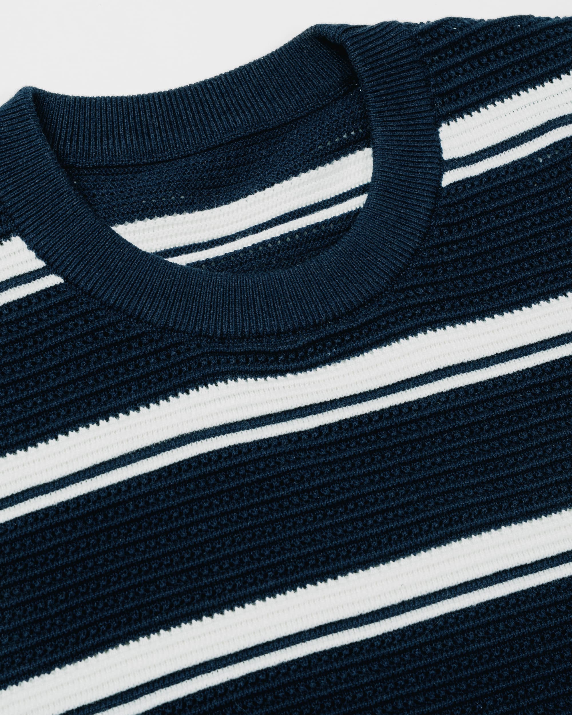 Close-up of a ribbed knit crewneck shirt with horizontal navy and white stripes, showing the collar and textured fabric detail.