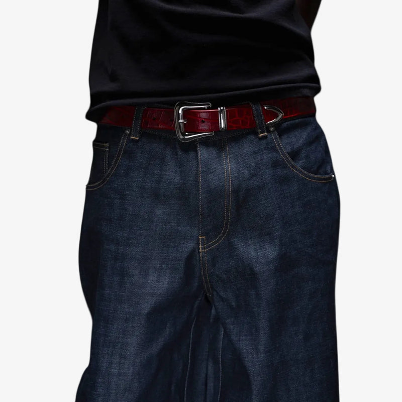 Dark blue jeans with a red croc belt on a white background