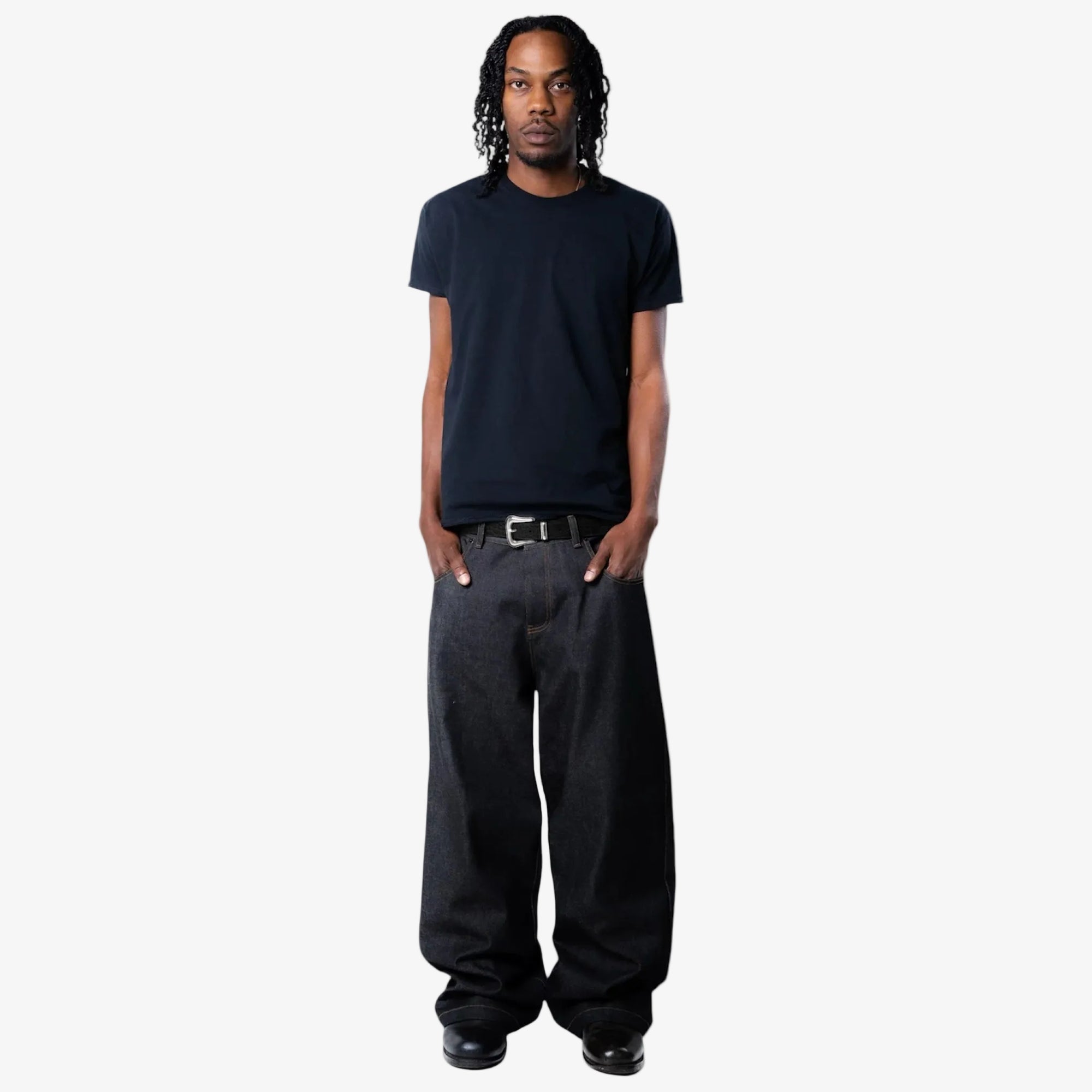 Man wearing a black t-shirt and dark pants with black croc embossed belt on a white background