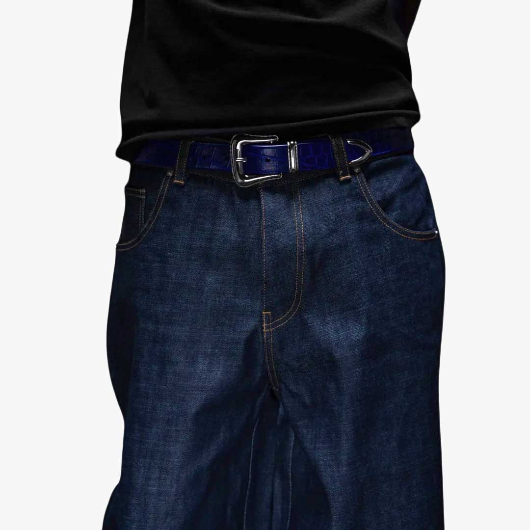 Person wearing dark blue jeans and a black shirt with a blue croc belt.